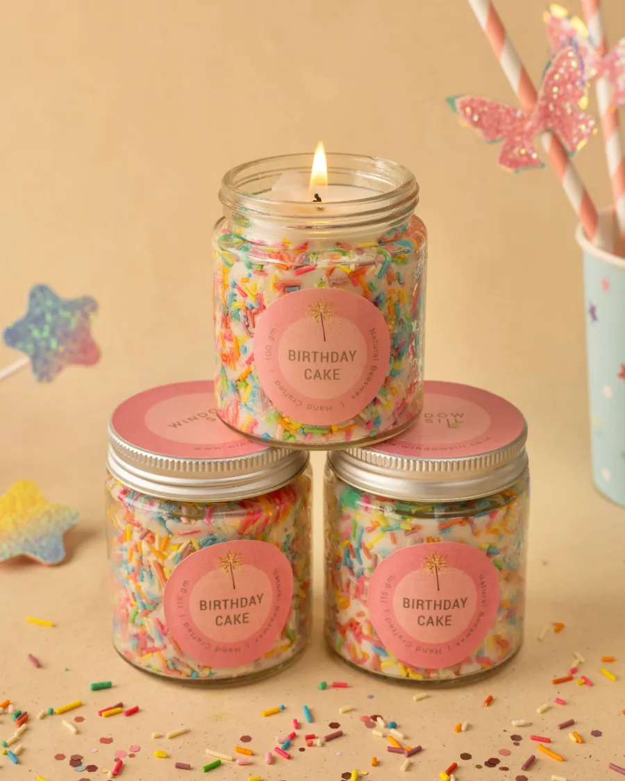 Birthday Cake Candles in glass jars by Windowsill, with colorful sprinkles and a lit candle, perfect for celebrations.