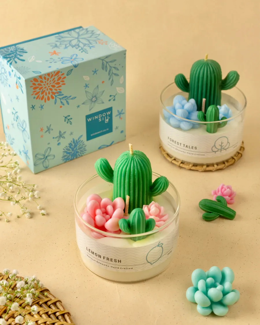 Cactus Garden Candles in glass jars by Windowsill, with cactus and floral designs, floral packaging, showcasing biophilia-inspired decor.