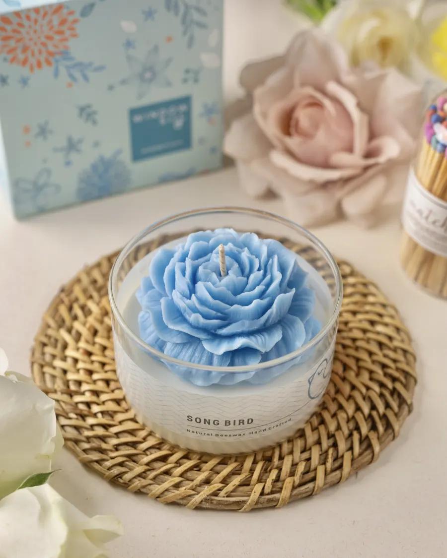 Blue peony candle in a glass jar by Windowsill, with floral packaging and matches, showcasing biophilia-inspired decor.