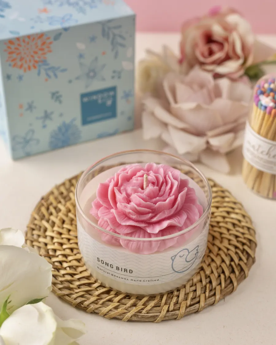 Pink peony candle in a glass jar by Windowsill, with floral packaging and matches, showcasing biophilia-inspired decor.